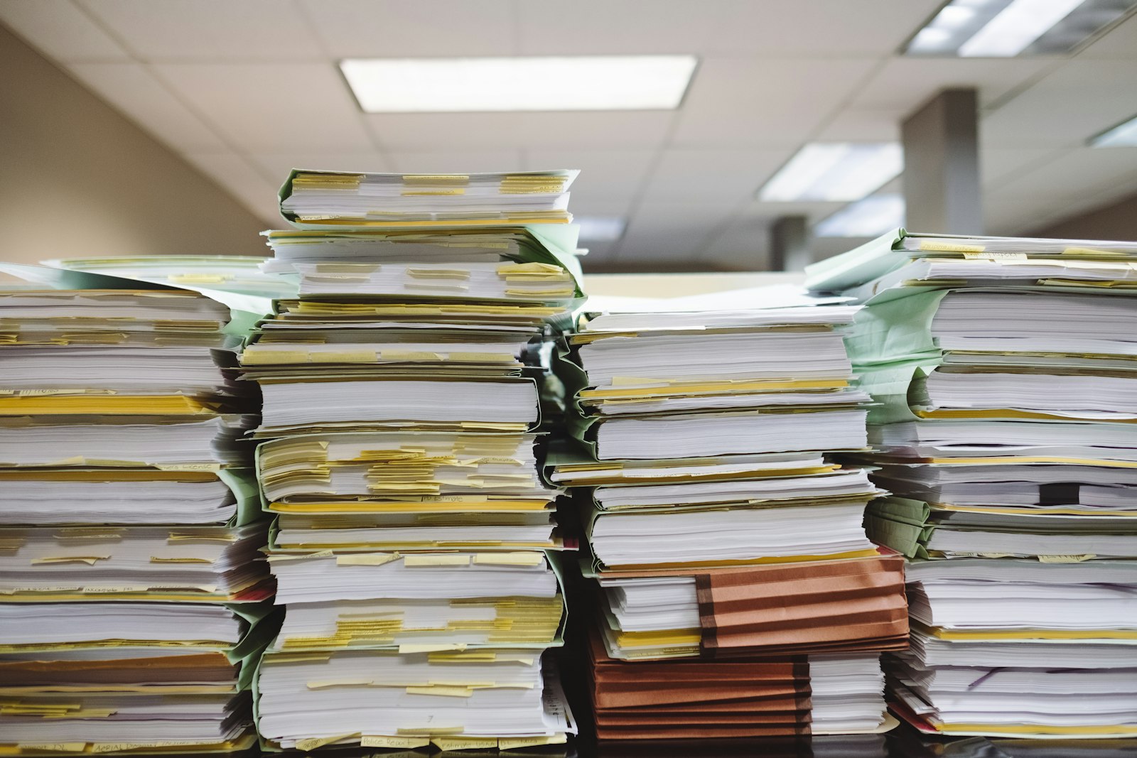 Stacks of paper documents and file folders piled on a surface.